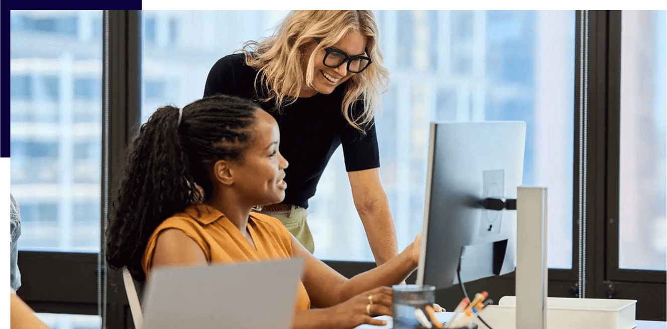 Two women collaborating on a project at a computer.