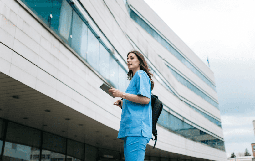 Person in scrubs walking outside modern building.