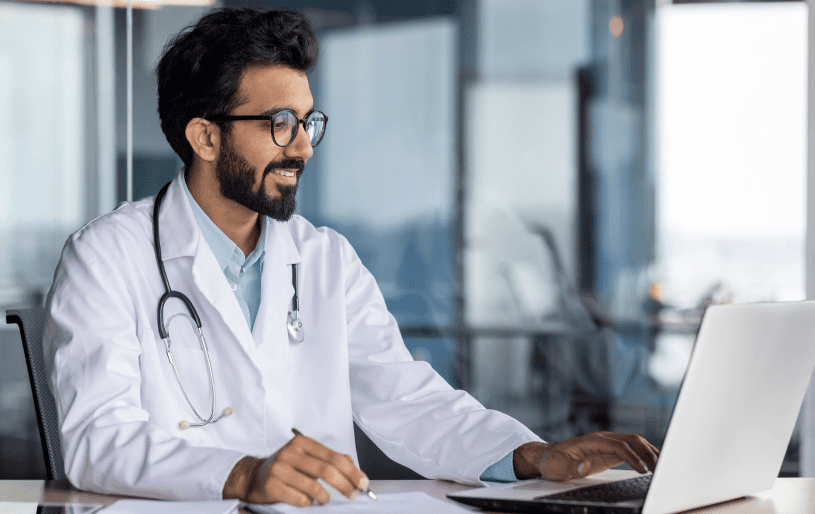 Doctor smiling while using a laptop.