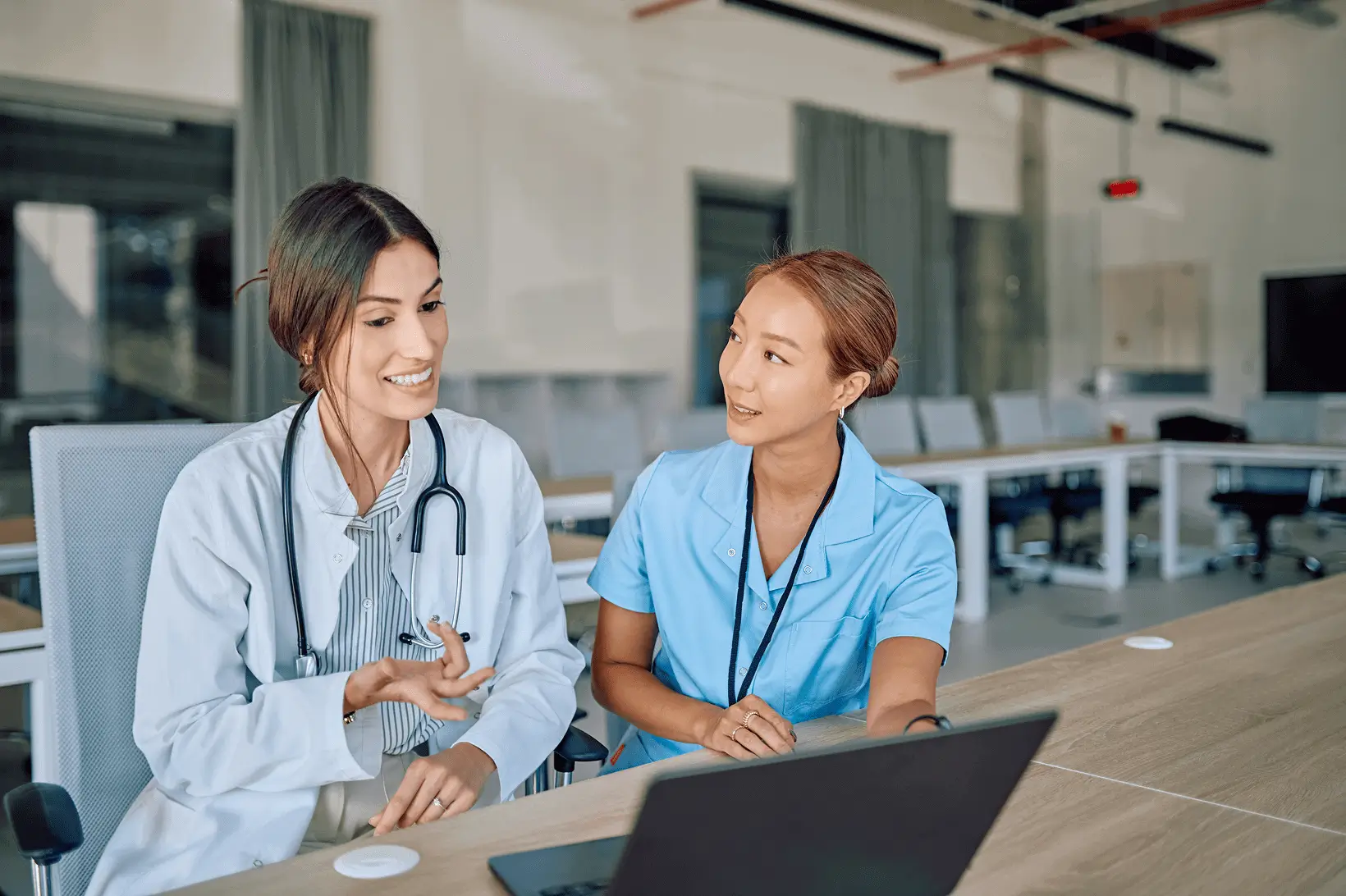Doctors discussing patient information on laptop.